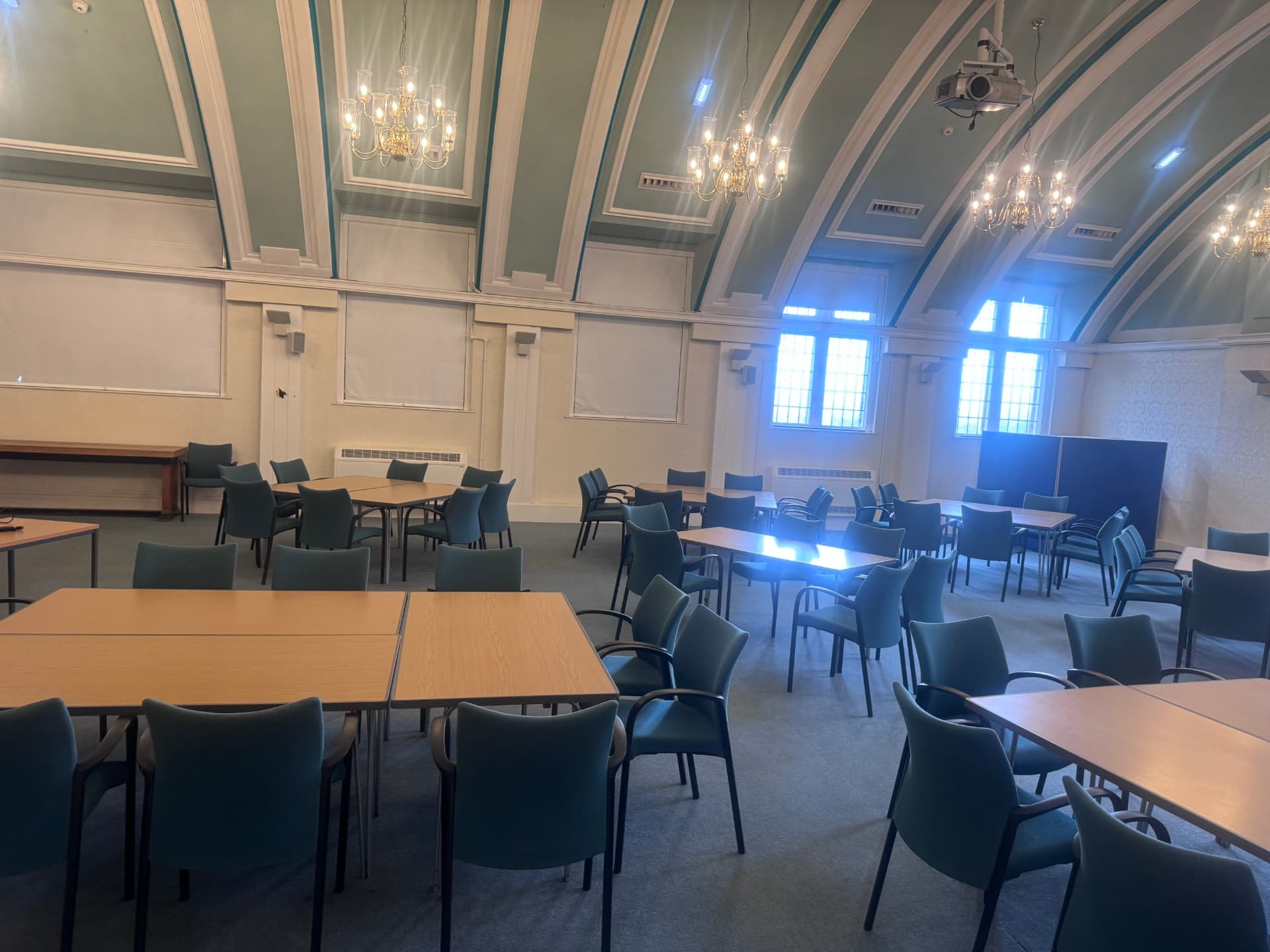 The main room at Hyde Town Hall with vaulted green ceilings, tables and seating arranged for community activities